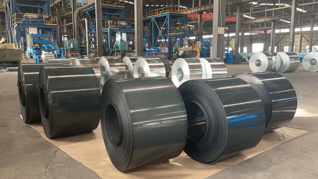 Black annealed CRC coils on factory floor with workers