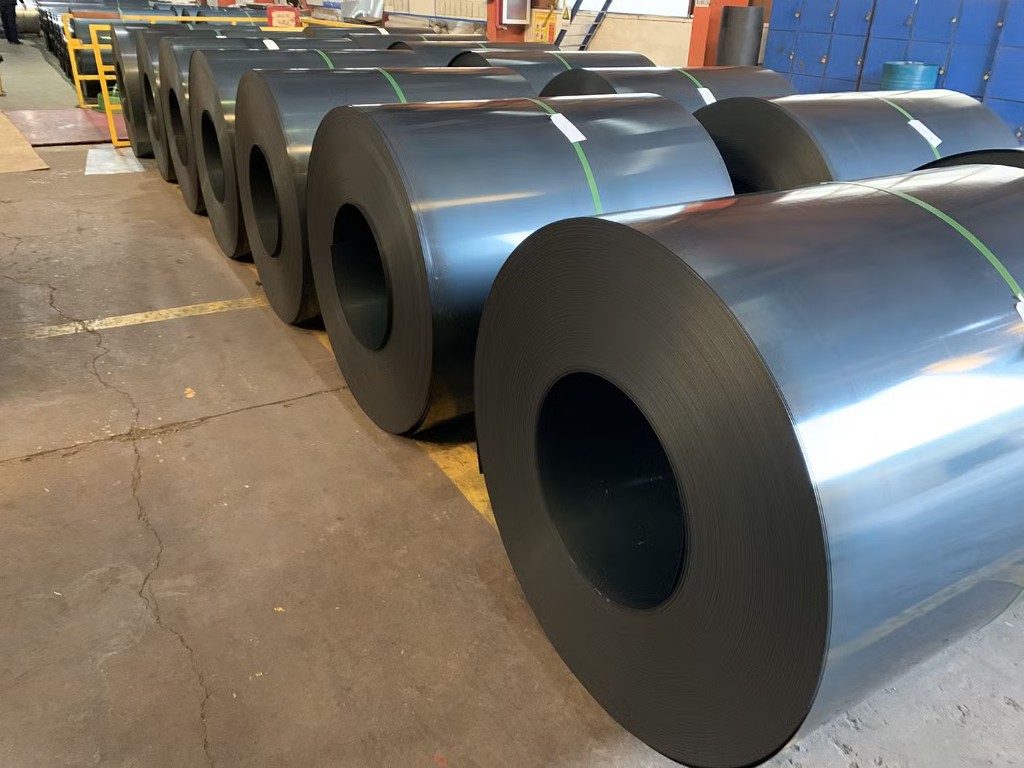 Dark annealed steel coils beside bright coils in plant